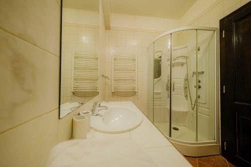 a white bathroom with a sink and a shower at Popasul Caprioarei in Pădureni