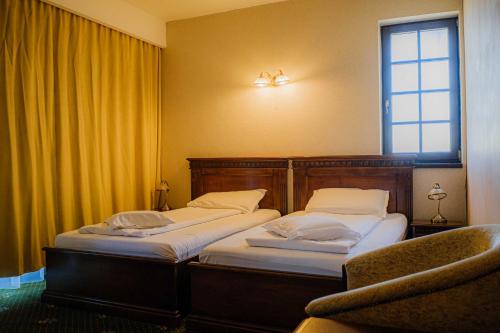 two twin beds in a room with a window at Popasul Caprioarei in Pădureni