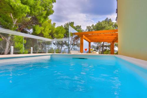 a large swimming pool with a wooden pergola at Sunset Luxury Beach Apartment - Private Pool in Ivan Dolac