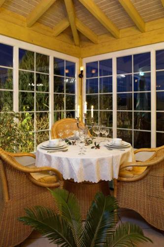a dining room table with a white table cloth and chairs at Hotel Villa Magnolia in Rödermark