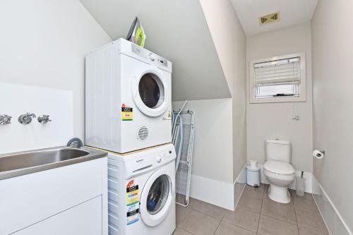 a white laundry room with a washer and dryer at Whale Tales at Caves Beach Villas in Caves Beach