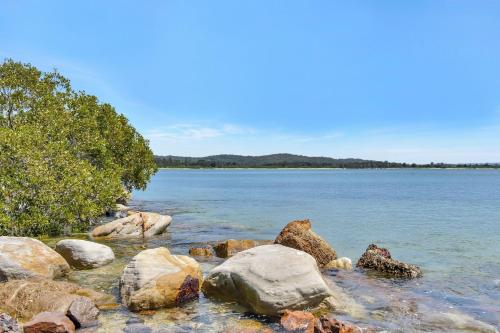 a group of rocks on the shore of a body of water at Whale Tales at Caves Beach Villas in Caves Beach