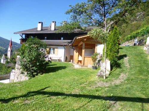 a house on a hill with a green yard at Hofer Hof in Feldthurns