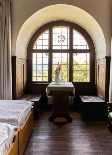 a room with two beds and a table and two windows at Castel Pergine in Pergine Valsugana