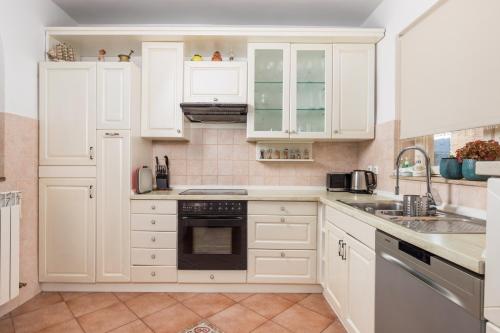 a white kitchen with white cabinets and a sink at Villa Magnolia Umag in Umag