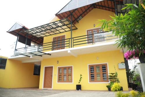 a yellow house with a balcony on top of it at Ameliore Horizon Nest in Pīrmed
