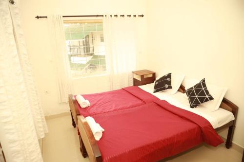 a bedroom with a red bed and a window at Ameliore Horizon Nest in Pīrmed