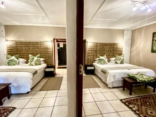 a bedroom with two beds and a doorway with two tables at Lidiko Lodge in St Lucia