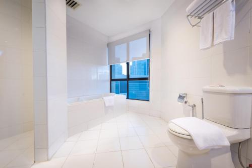a white bathroom with a toilet and a window at Hotel Sentral KL @ KL Sentral Station in Kuala Lumpur