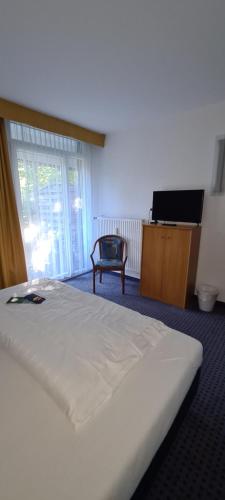 a bedroom with a white bed and a tv at Aparthotel Höper in Oyten