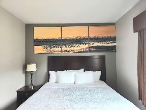 a hotel room with a bed and a painting on the wall at Days Inn by Wyndham Kemah in Kemah