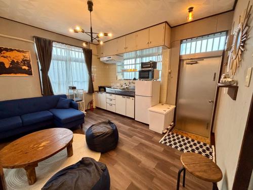 a living room with a blue couch and a kitchen at Ohaco Hostel Ishigaki in Ishigaki Island
