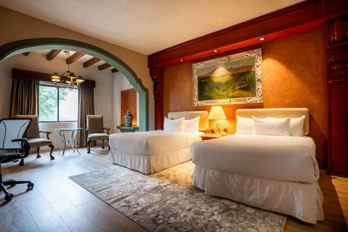 Un dormitorio con dos camas y una mesa y sillas. en Hilton San Luis Potosi, en San Luis Potosí