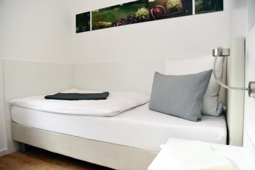 a bed in a white room with a pillow on it at Hotel am alten Park in Augsburg