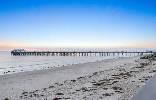a beach with a pier in the water at Sams Henley Beach Garden Unit in Henley Beach