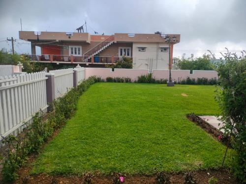a yard with a fence and a house at Blissfull Meadows in Ooty