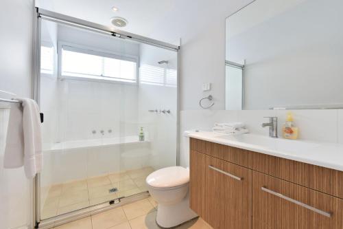 a bathroom with a toilet and a shower and a sink at Blue Lagoon at Caves Beach Villas in Caves Beach