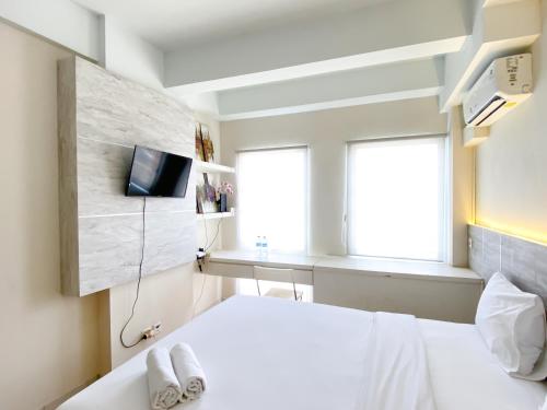 a bedroom with a white bed and a television at Modern Look and Comfy Studio Patraland Urbano Apartment By Travelio in Bekasi