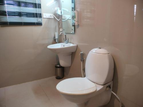 a bathroom with a white toilet and a sink at Blissfull Meadows in Ooty