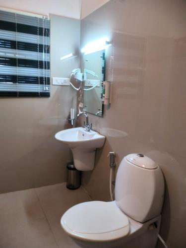 a bathroom with a white toilet and a sink at Blissfull Meadows in Ooty