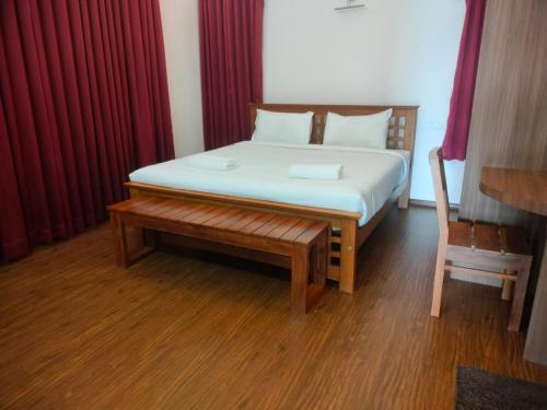 a bedroom with a bed with a bench and red curtains at Blissfull Meadows in Ooty