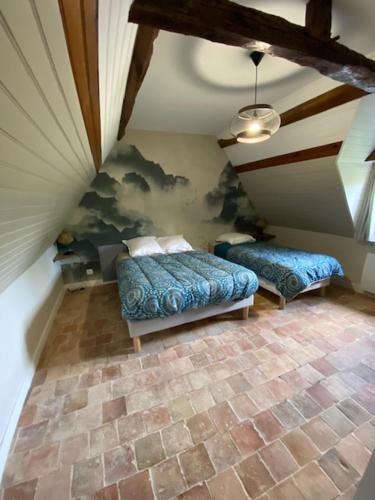 a attic room with two beds and a ceiling at Domaine de la Maroutière in Saint-Fort