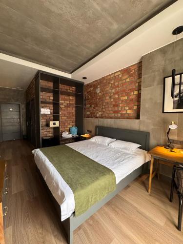 a bedroom with a large bed and a brick wall at Bugu Hotel Bishkek in Bishkek