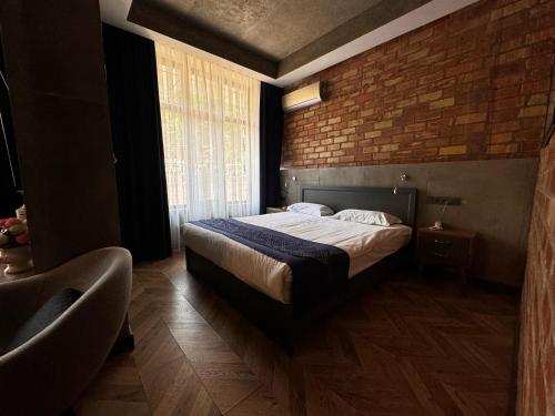 a bedroom with a bed and a brick wall at Bugu Hotel Bishkek in Bishkek