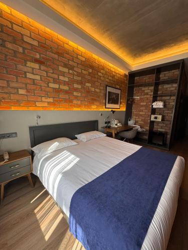 a bedroom with a large bed and a brick wall at Bugu Hotel Bishkek in Bishkek