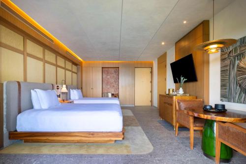a bedroom with a bed and a desk and a television at Waldorf Astoria Costa Rica Punta Cacique in Playa Hermosa
