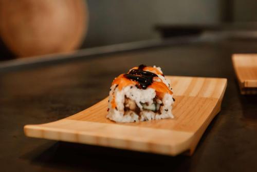 a piece of sushi on a wooden plate on a table at Wyndham Alltra Samana All Inclusive Resort in Las Galeras