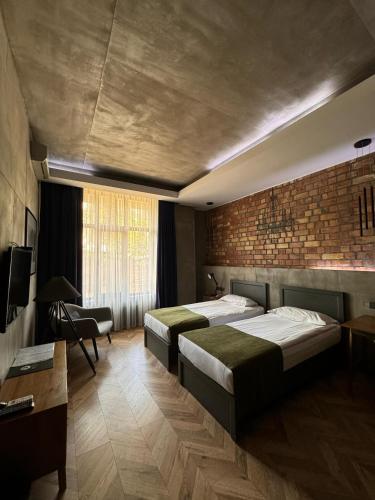 a bedroom with two beds and a brick wall at Bugu Hotel Bishkek in Bishkek