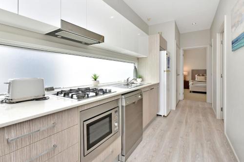 a kitchen with a stove top oven next to a hallway at Sandy Isles at Caves Beach Villas in Caves Beach
