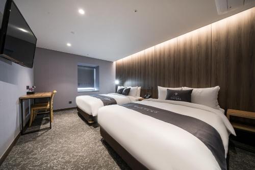 a hotel room with two beds and a flat screen tv at Layers Hotel Busan Hadan in Busan