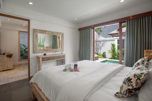 a bedroom with a large bed and a mirror at Two Lizards Beach Villas in Sanur