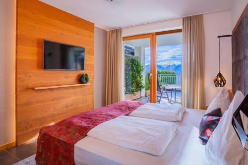 a bedroom with a bed with a television and a balcony at Gattererhof in Schenna