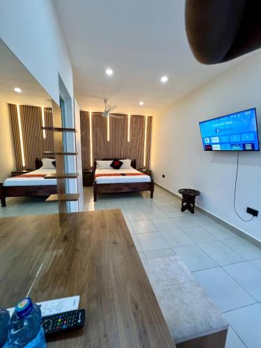 a living room with two beds and a tv on the wall at The Beach House by Maasai in Mombasa