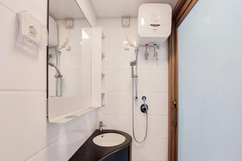a bathroom with a shower with a toilet and a sink at Cozy Style Studio Room at High Floor Sky House BSD Apartment By Travelio in Tangerang