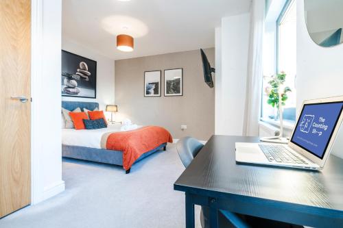 a bedroom with a bed and a desk with a laptop at TheCountingSheep - Heathrow in 15 mins - Glass Balcony - Dedicated Workspace in Hounslow
