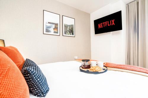a hotel room with a bed with a tray of food at TheCountingSheep - Heathrow in 15 mins - Glass Balcony - Dedicated Workspace in Hounslow