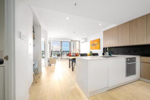 a kitchen with white cabinets and a dining room with a table at Luxe Flemington Cityscape Racecourse views Pool Gym Parking in Melbourne