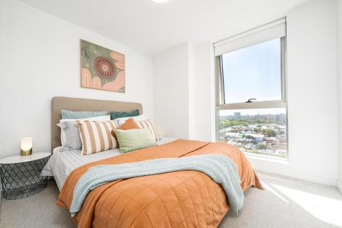 une chambre avec un lit et une grande fenêtre dans l'établissement Luxe Flemington Cityscape Racecourse views Pool Gym Parking, à Melbourne