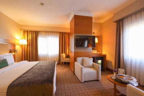 a hotel room with a large bed and a chair at Tugcan Hotel in Gaziantep