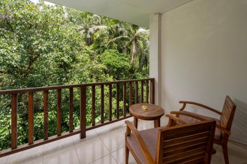a balcony with a table and chairs and a window at Pertiwi Bisma 1 in Ubud