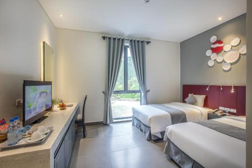 a hotel room with two beds and a flat screen tv at Thanh Tan Hot Springs By Fusion in Hue