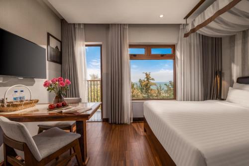 a hotel room with a bed and a desk and a window at HA Ocean Front Hotel and Apartment in Hoi An