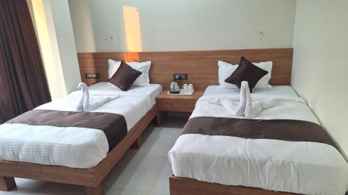 a hotel room with two beds with white towels at Hotel Momon in Guwahati