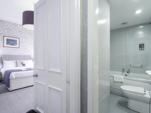 a bathroom with a sink and a toilet and a bed at Glenspey in Kingussie