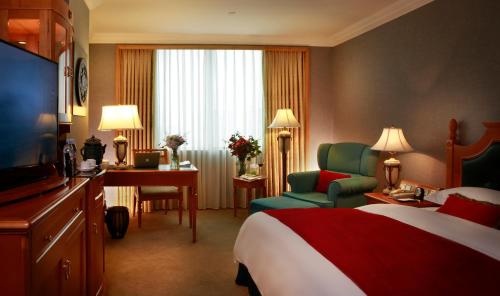 a hotel room with a bed and a chair and a desk at Grand Noble Hotel Dongguan in Dongguan
