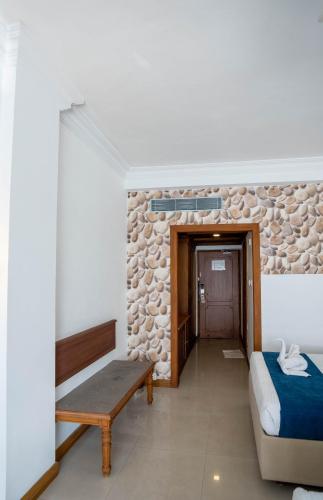 a bedroom with a bed and a bench and a stone wall at Casino Hotels Ltd in Trichūr